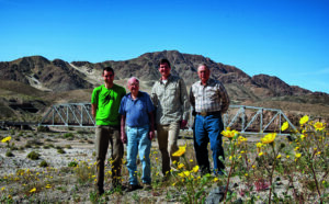 BLM Sacramento environmental specialist Mike Sintetos, lifelong rockhound Bill Depue, Mojave Trails monument manager Kyle Sullivan, and rockhound Joe Sumners with the train trestle near the Afton Canyon campground in the background during the superbloom of 2019. Photo: Lisbet Thoresen.
